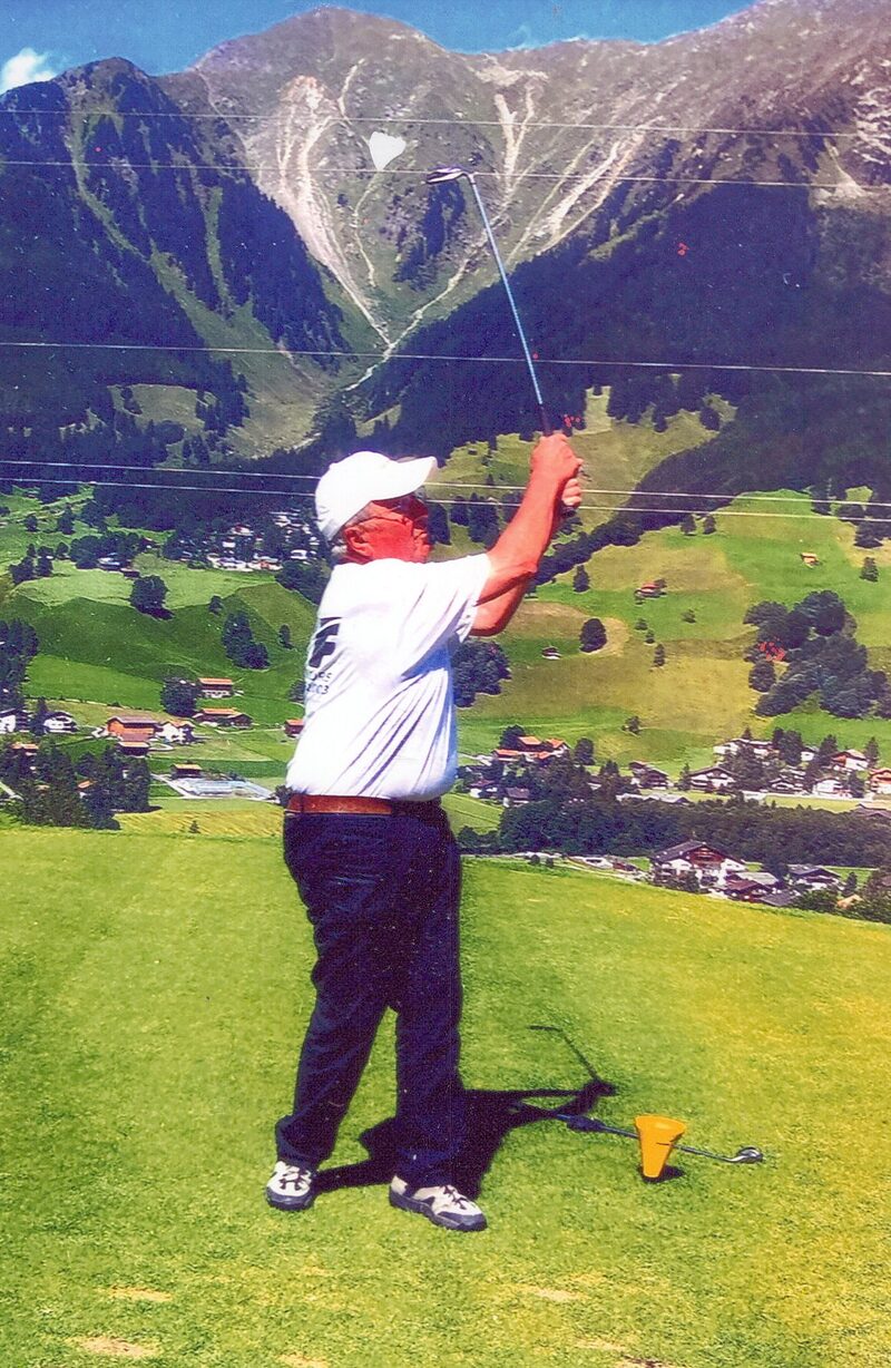 Sepp Bergamin im Golf-Abschlag, weisses Cap, vor Bündner Bergpanorama
